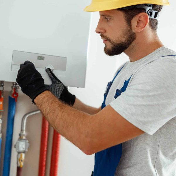 Serious technician setting the new gas boiler for hot water and heating. Manual work, maintenance concept